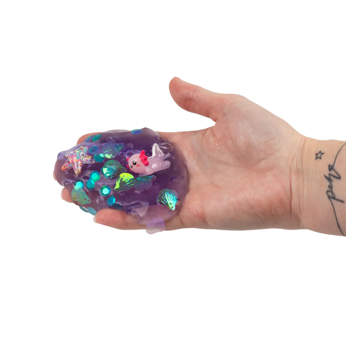 Hand holding a purple glittery slime with a unicorn design on a white background