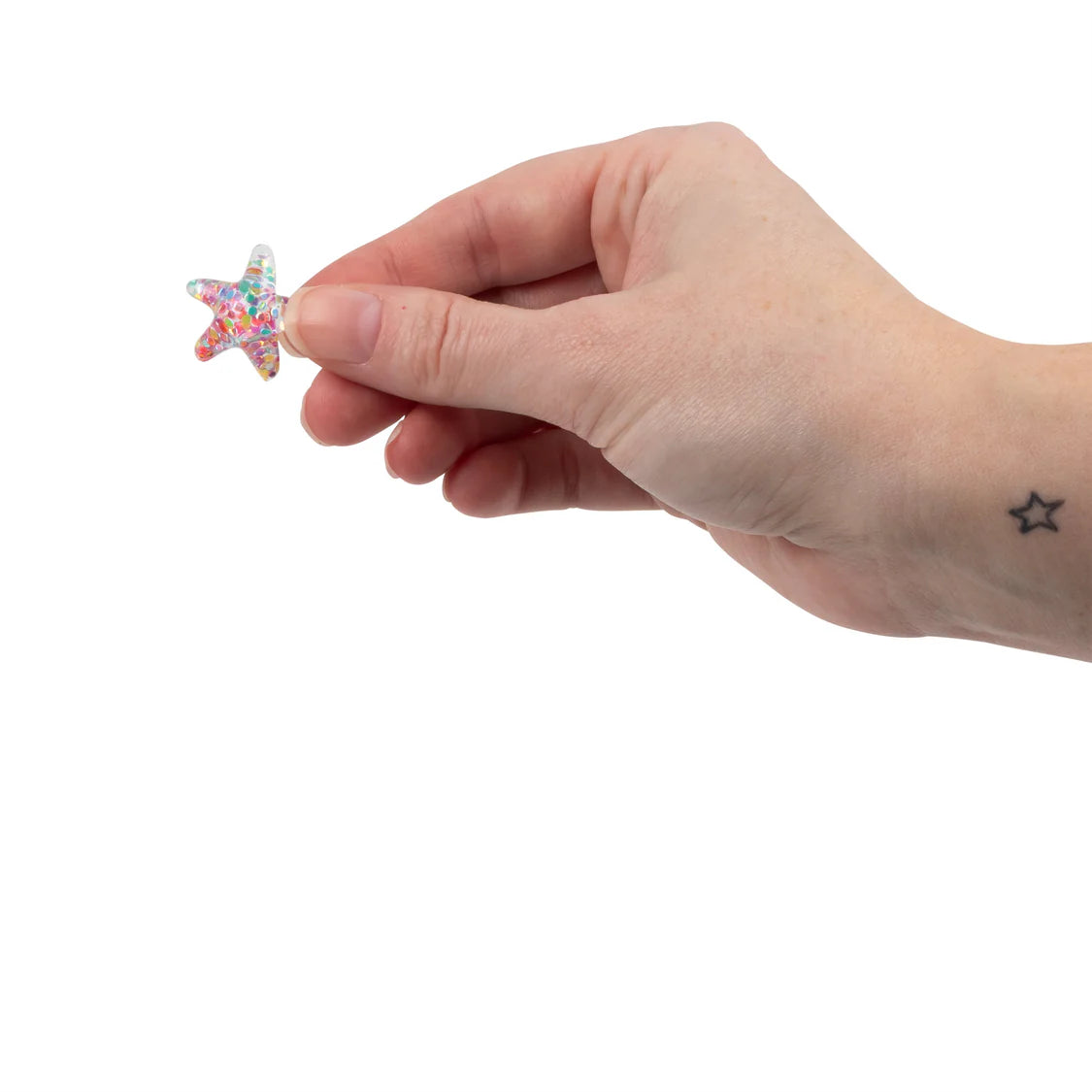 Hand holding a small star-shaped object with colorful sprinkles on a white background