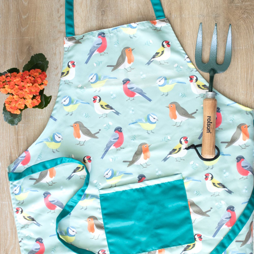 Apron with bird pattern and gardening tools on a wooden surface