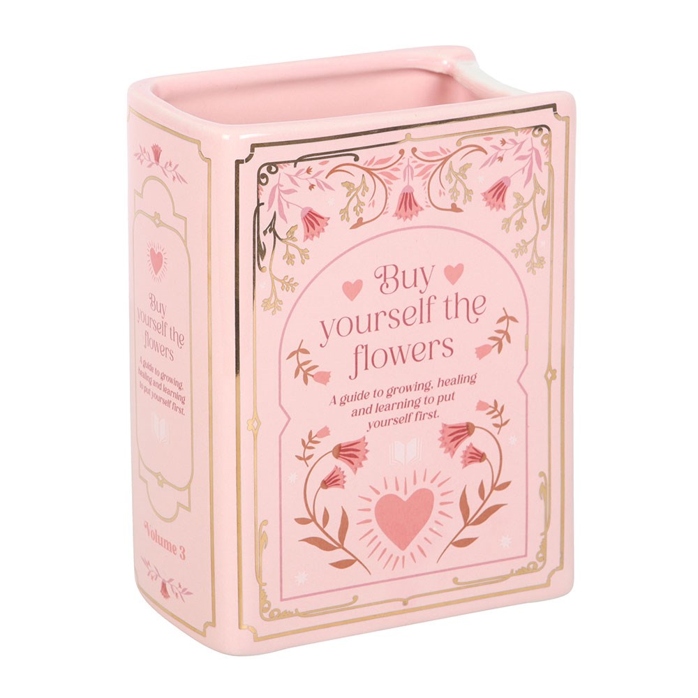 Pink ceramic book shaped vase with floral design and text on a white background