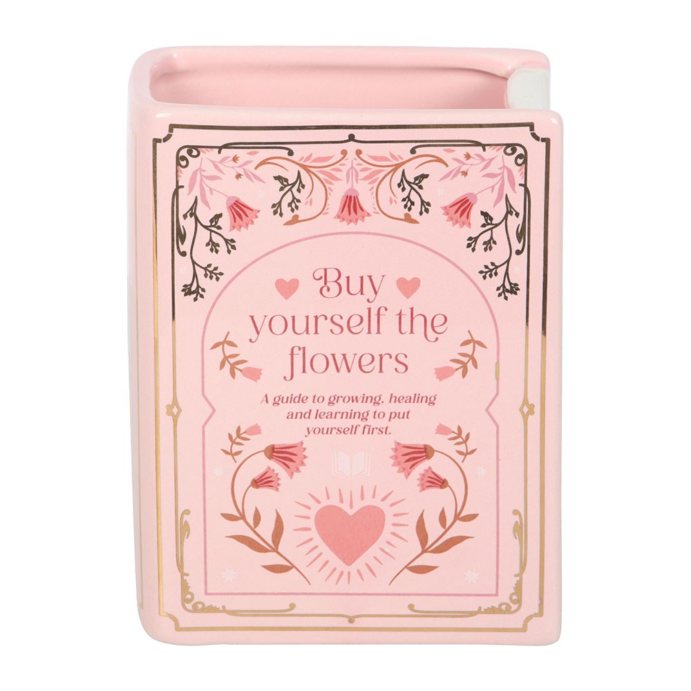 Pink book shaped vase titled 'Buy Yourself the Flowers' with floral design on a white background