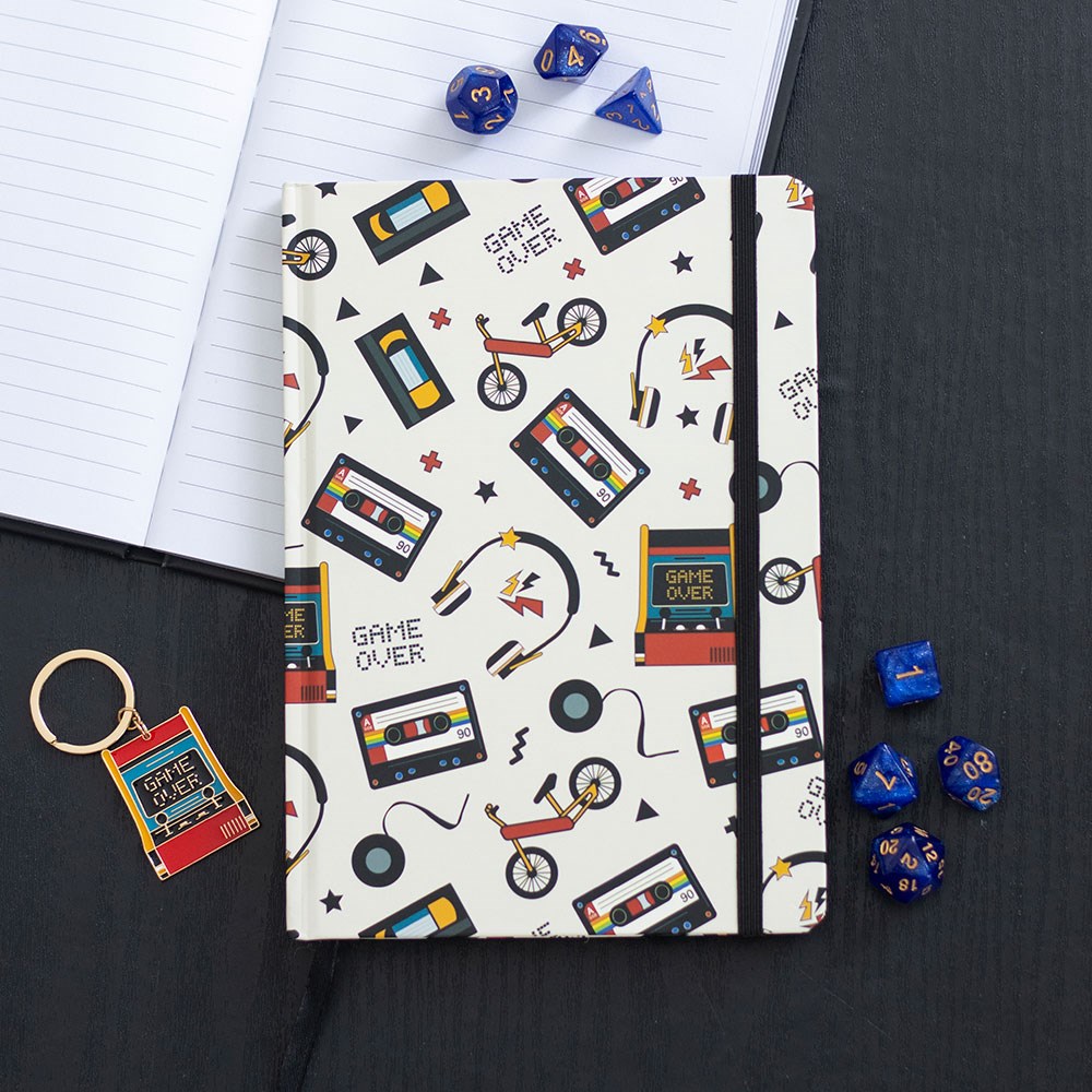 Notebook with retro-themed design on a black surface with dice and keychain.