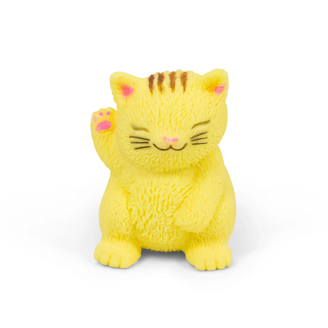 A small yellow cat figurine with closed eyes, a raised paw, pink inner ears and paw pads, and brown stripes on its forehead, photographed on a clean white background.