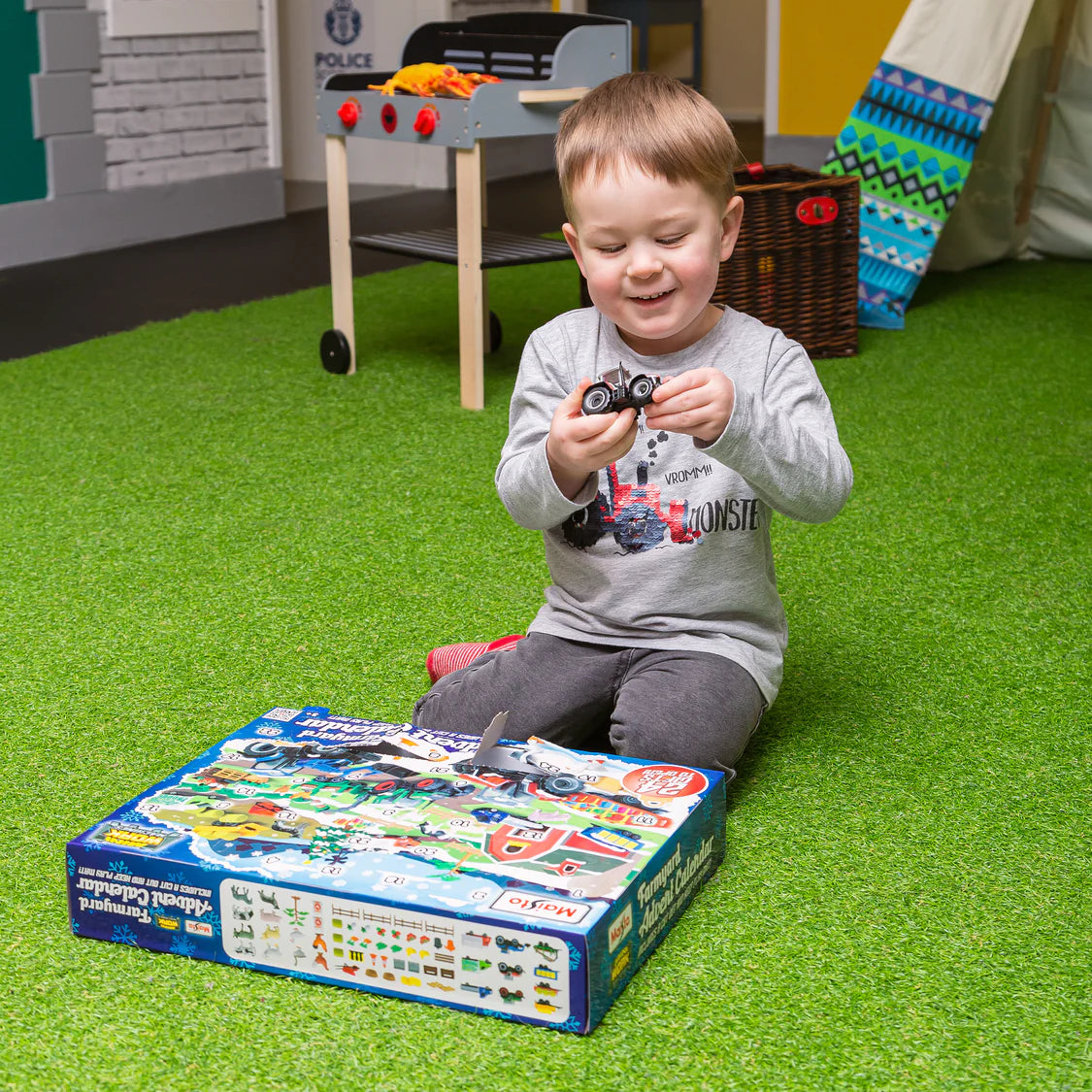 Child playing with toy cars on a box in a playroom