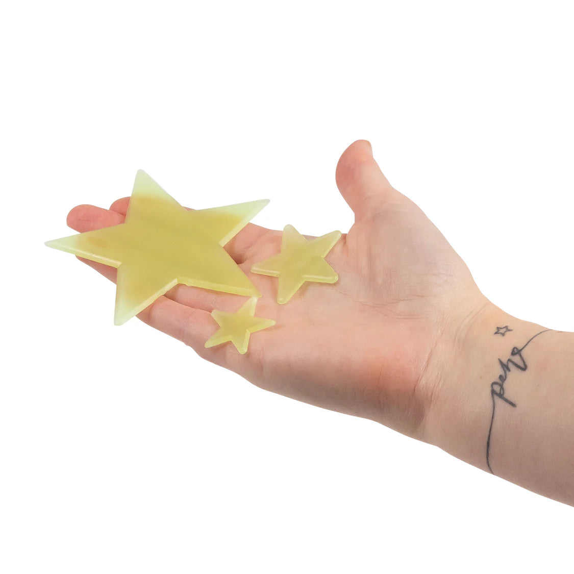 Hand holding three yellow star-shaped objects against a white background