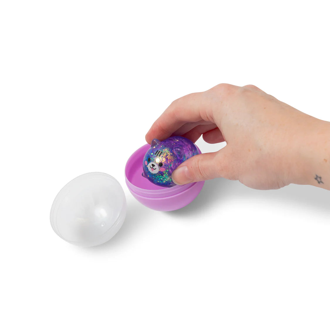Hand holding a purple toy with a colorful ball inside on a white background
