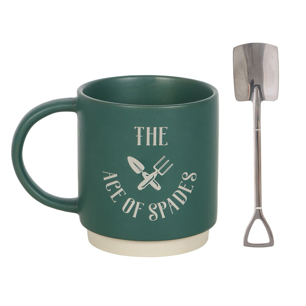 Green mug with 'The Age of Spades' text and gardening tools, next to a small metal spade on a white background.