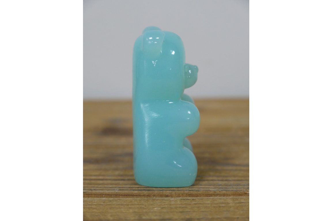 Turquoise bear on a wooden surface with a white background
