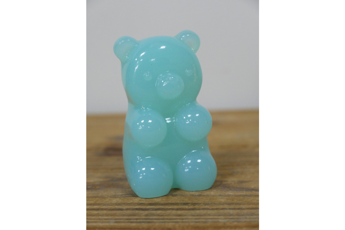 Gummy bear-shaped object on a wooden surface with a white background