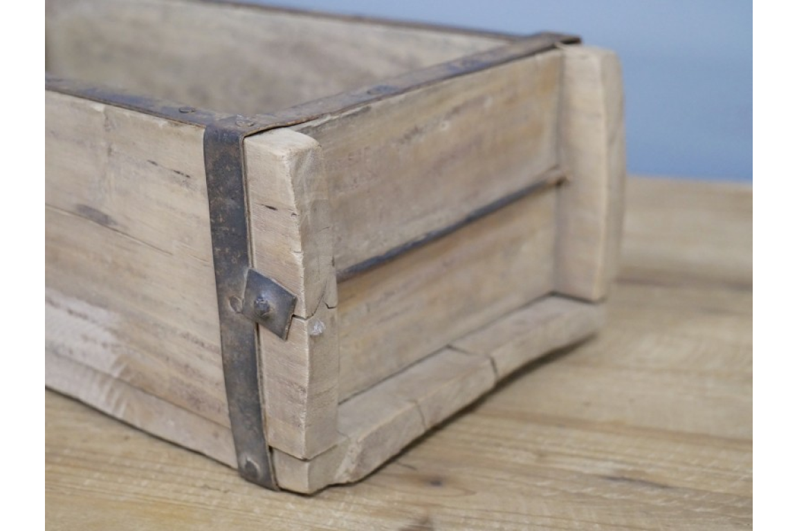 Wooden brick mould with metal bands on a wooden surface