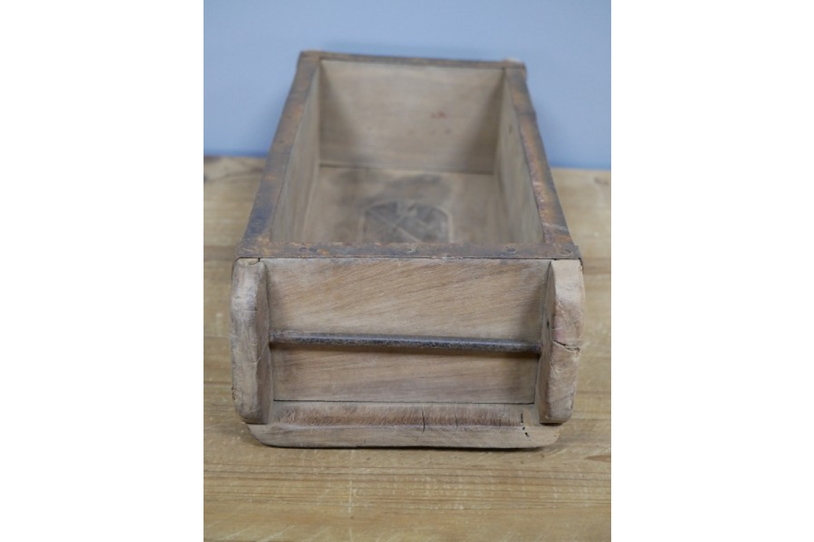 Wooden brick mould planter box on a wooden surface with a light blue wall background