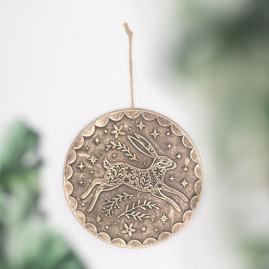 Decorative bronze terracotta hanging with a hare design on a blurred green background
