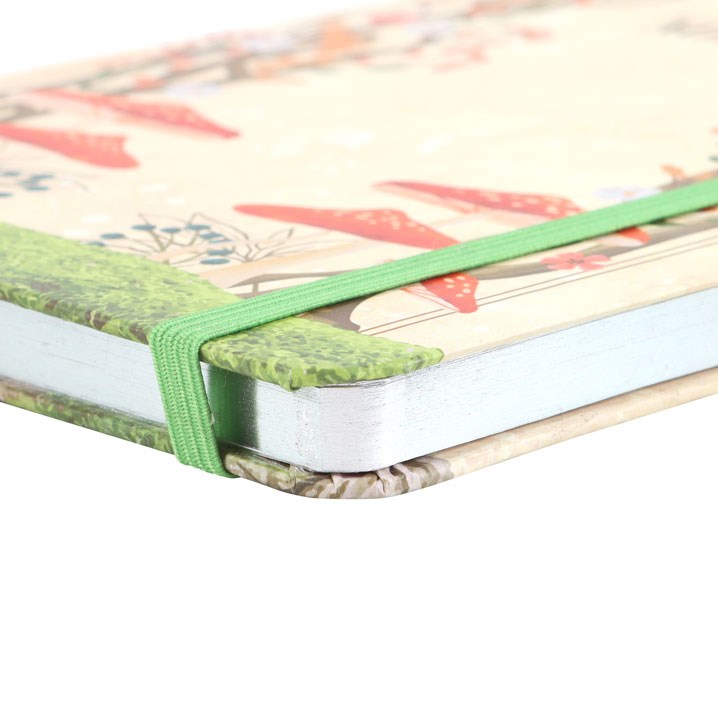 Close-up of a notebook with a colorful floral design on the cover and a green elastic band.