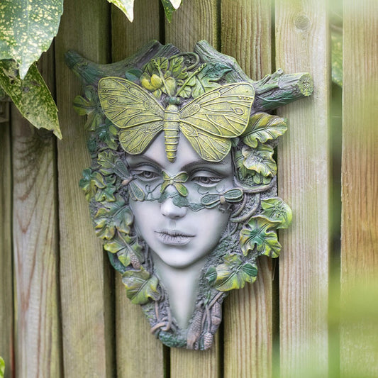 Decorative wall art of a face with leaves and a butterfly on a wooden background