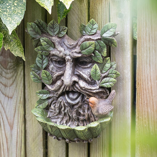 Decorative wall piece with a face made of leaves and a bird on a wooden background