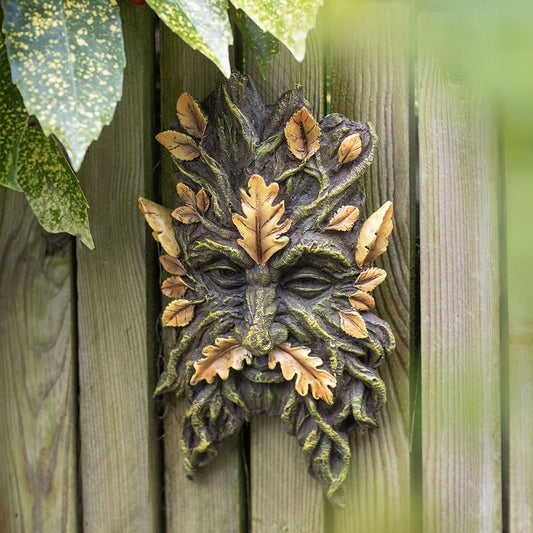 Decorative greenman face with leaves on a wooden background