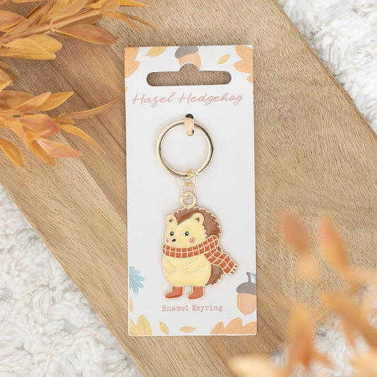 Hedgehog keychain on a decorative card with autumn leaves and acorns.