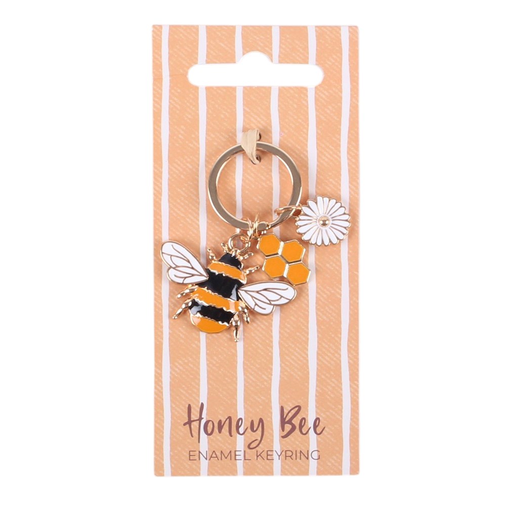 A honey bee enamel keyring with a gold-tone split ring, featuring a detailed bee charm with orange and black stripes, white wings, a small white daisy, and orange hexagon beads, all attached to a peach and white vertically striped card labeled 'Honey Bee ENAMEL KEYRING'.