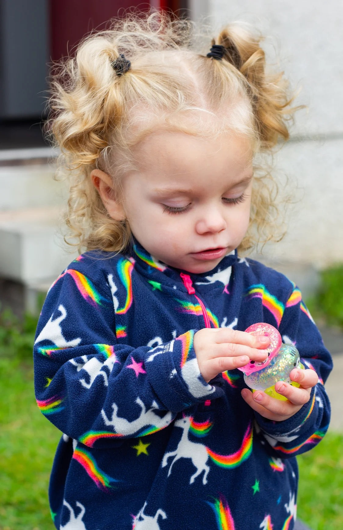 Child wearing a colourful sweater with rainbow patterns, playing outdoors with Scrunchems Sugar Squishy Kitties