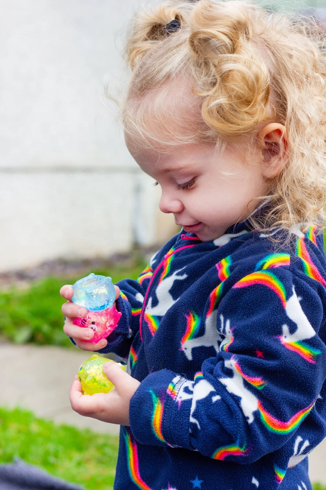 Child wearing a colourful sweater with rainbow patterns, playing outdoors with Scrunchems Sugar Squishy Kitties