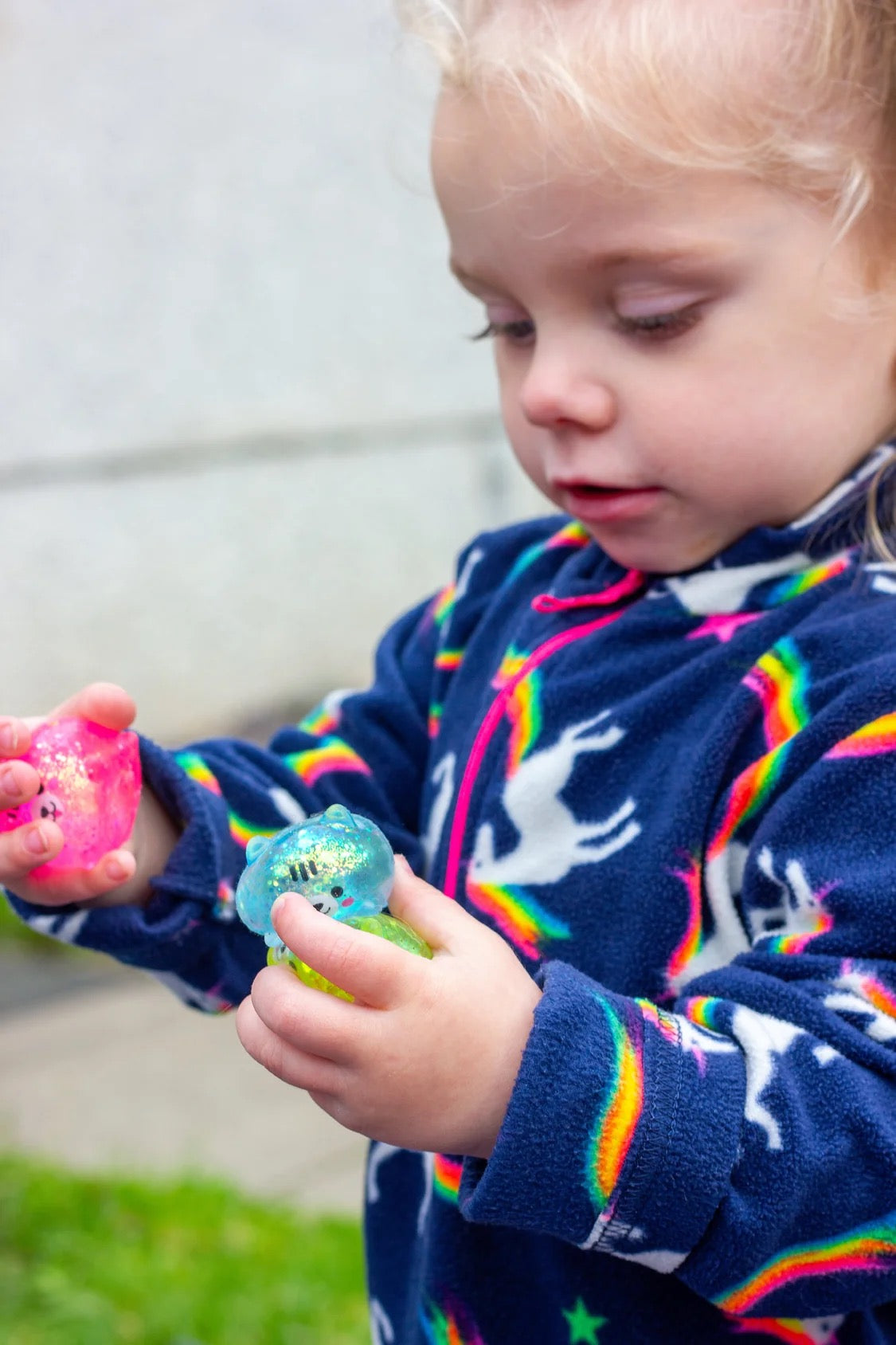 Child wearing a colourful sweater with rainbow patterns, playing outdoors with Scrunchems Sugar Squishy Kitties