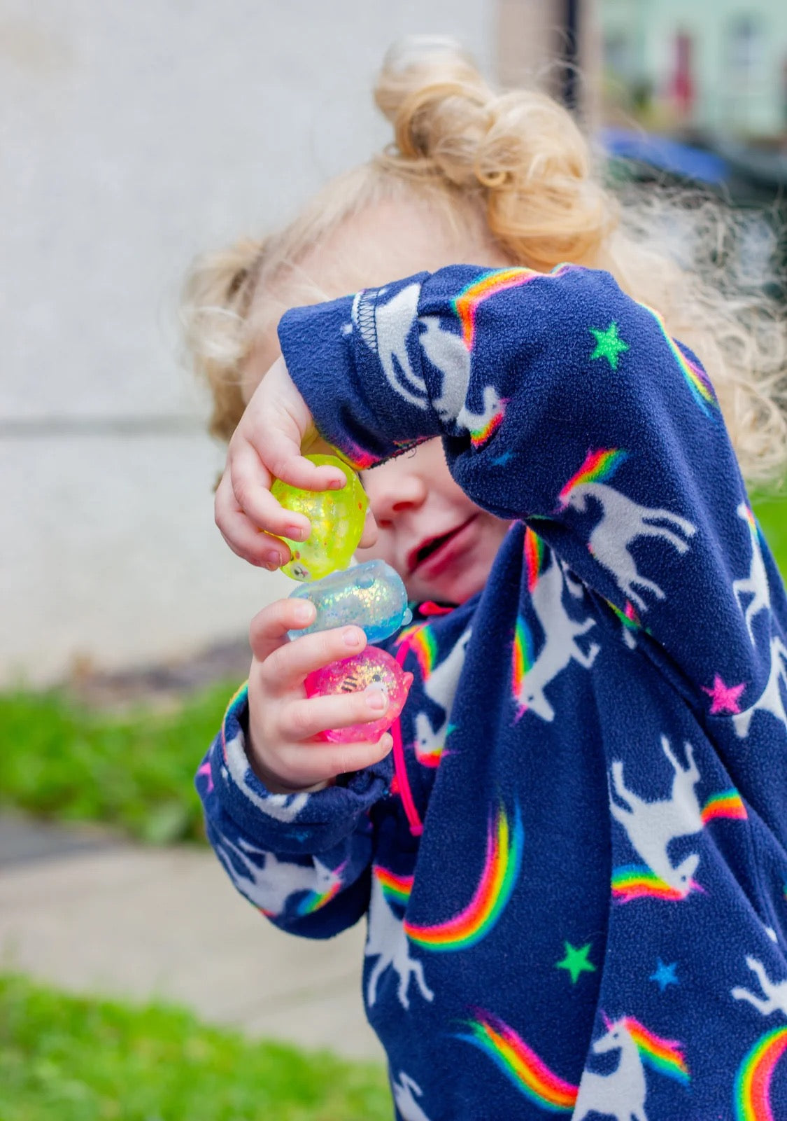 Child wearing a colourful sweater with rainbow patterns, playing outdoors with Scrunchems Sugar Squishy Kitties