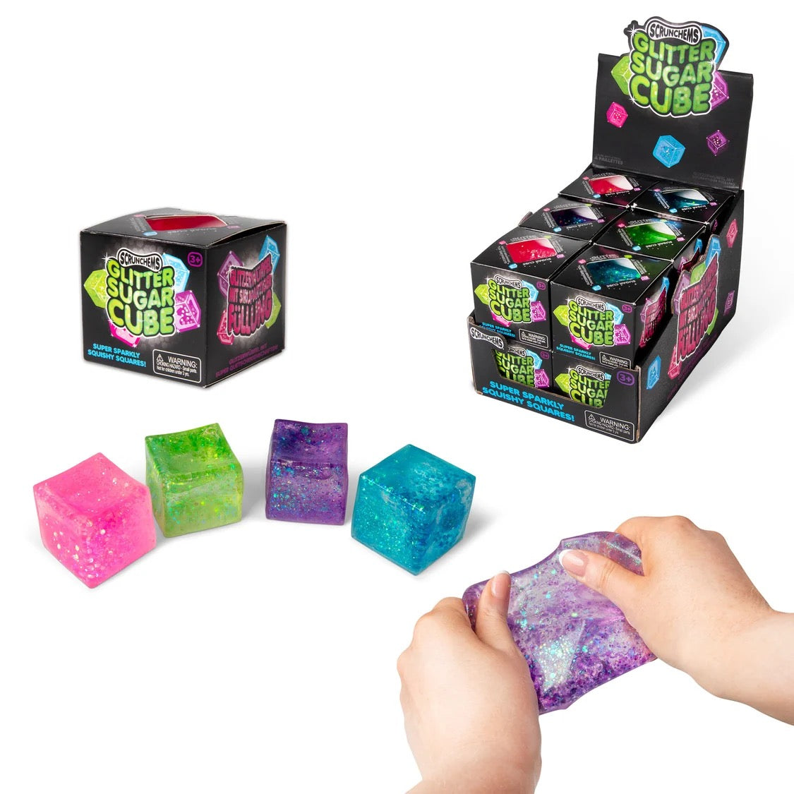 Colourful glittery sugar cubes with packaging and a hand holding one cube.
