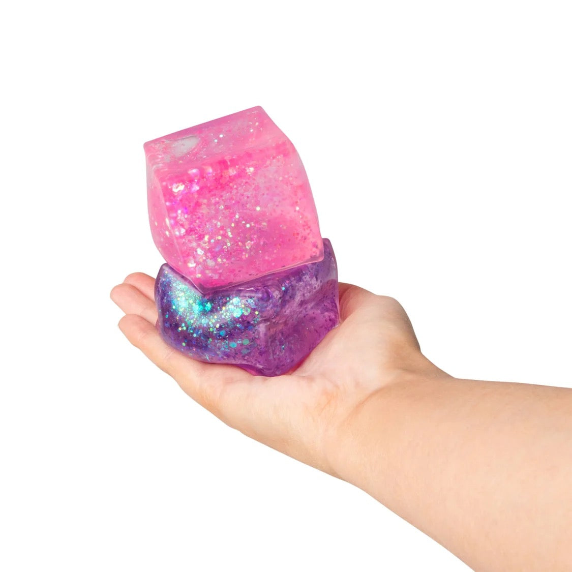 Hand holding pink and purple Scrunchems Glitter Cubes against a white background