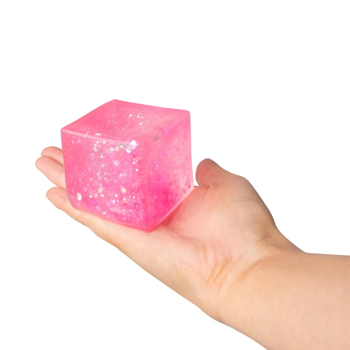 Pink glittery cube held in a hand against a white background