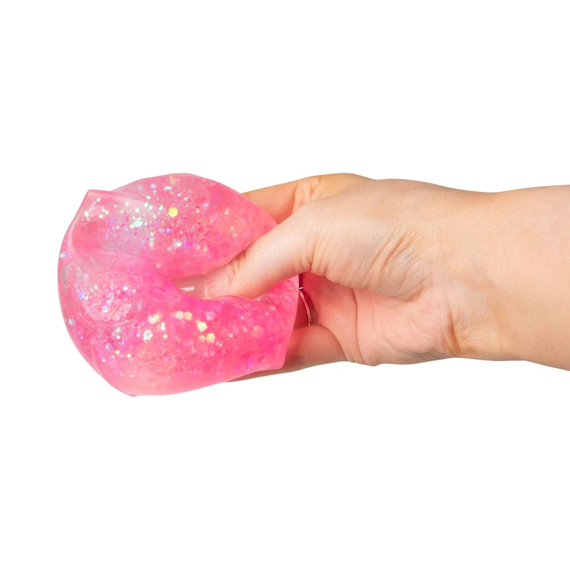 A hand holding a translucent pink Scrunchems Glitter Cube against a plain white background.