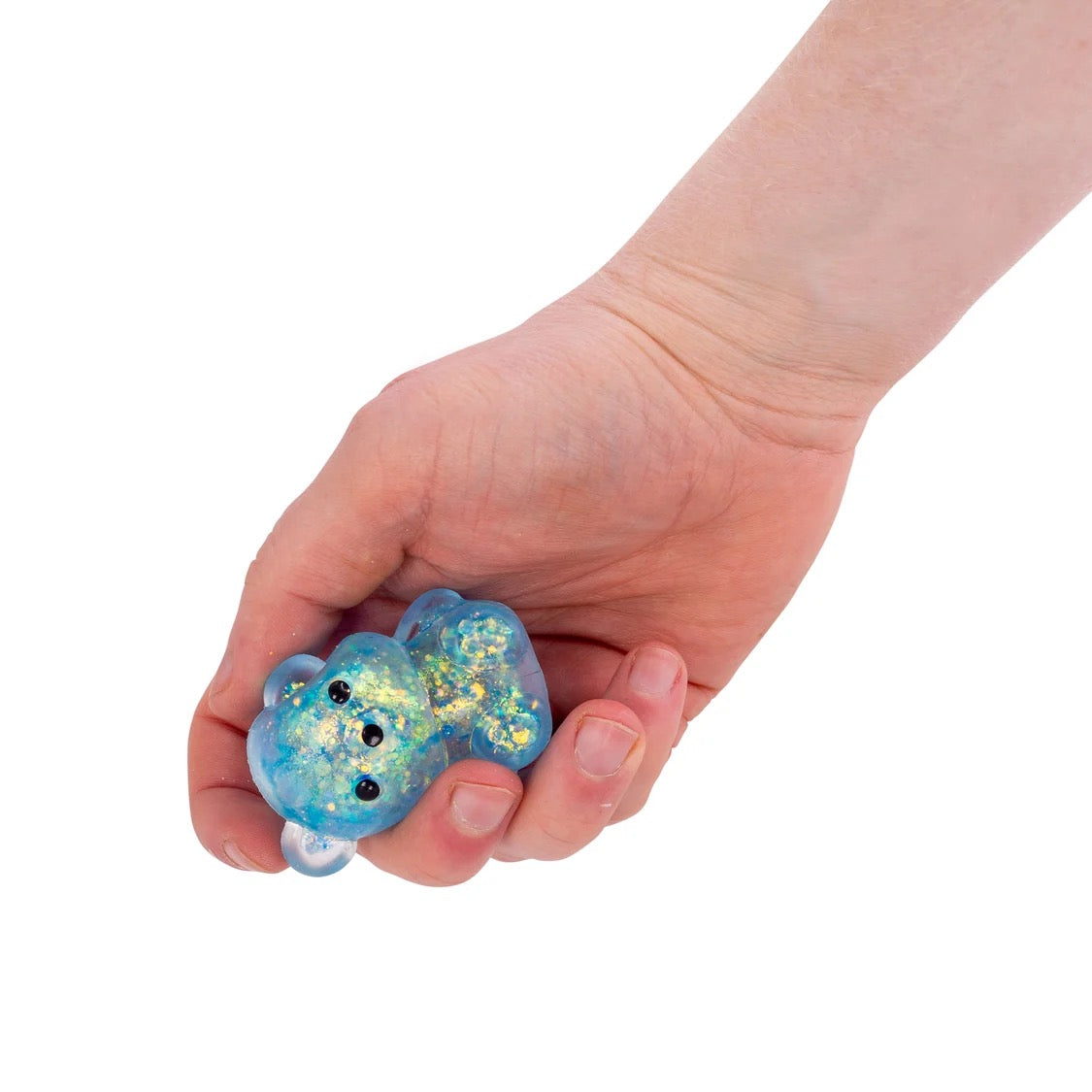 Hand holding a small blue Scrunchems Squishy Sugar Bear with glitter on a white background