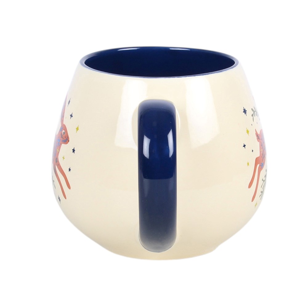A cream mug with dark blue handle and a picture of a leaping hare with greenery and stars around it. 