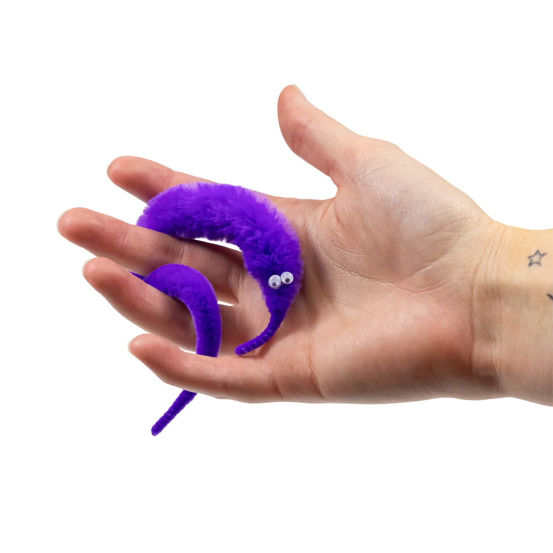 Purple fuzzy caterpillar toy held in a hand against a white background