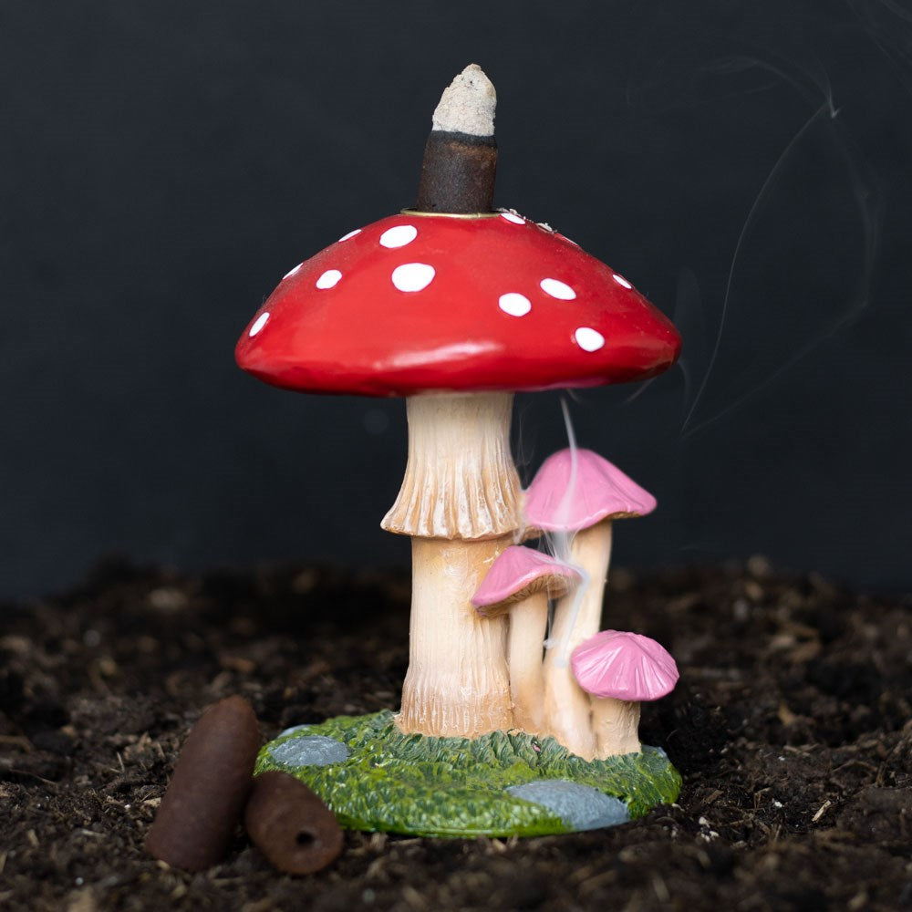 Mushroom-shaped incense burner with red cap and white spots on a dark background