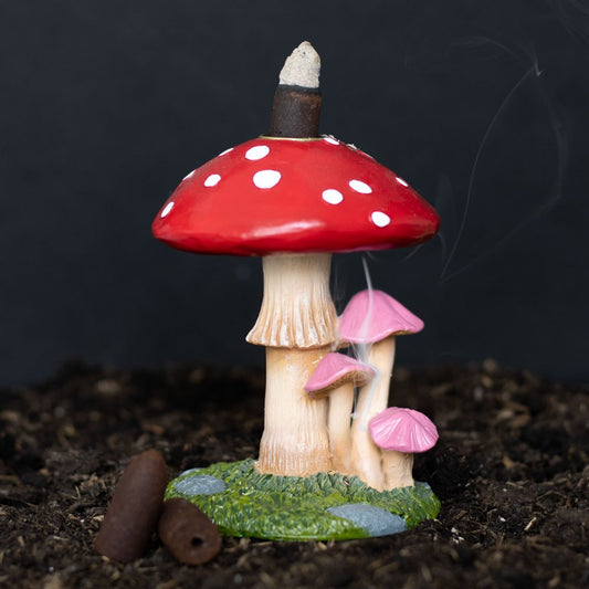 Mushroom-shaped incense burner with red cap and white spots on a dark background