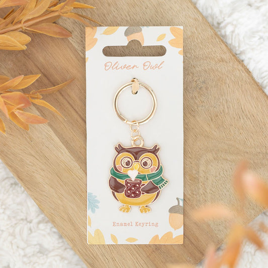 Owl keychain on a branded card with autumn leaves in the background