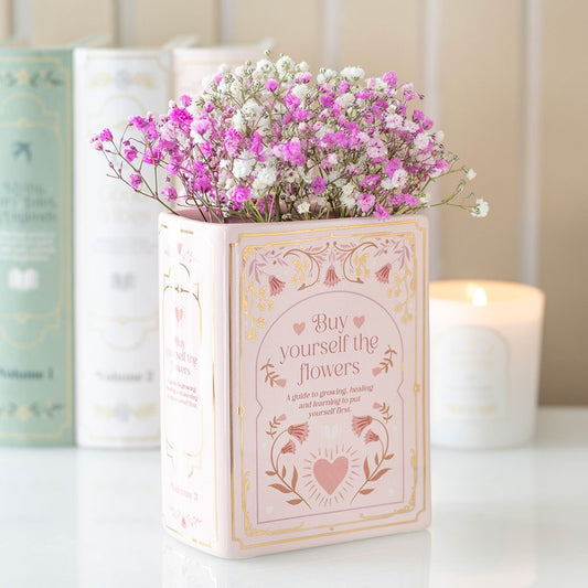 Decorative book shaped vase with pink and white flowers on a light background