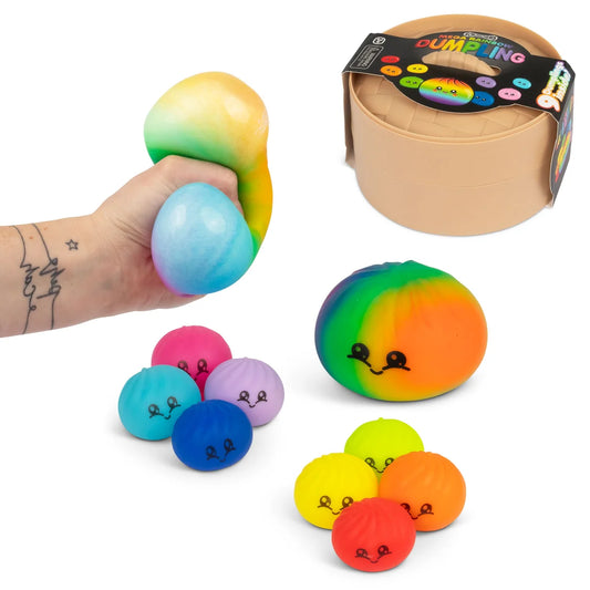 A set of rainbow-coloured squishy dumplings with cartoon faces, shown with a hand squeezing one ball, a small tan storage container with a colourful label, and several loose balls in different colours on a white background.