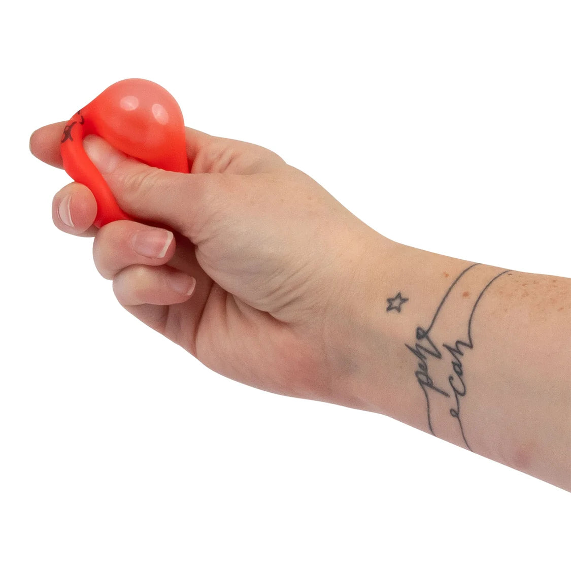A hand squeezing a small red scrunchems dumpling against a plain white background.