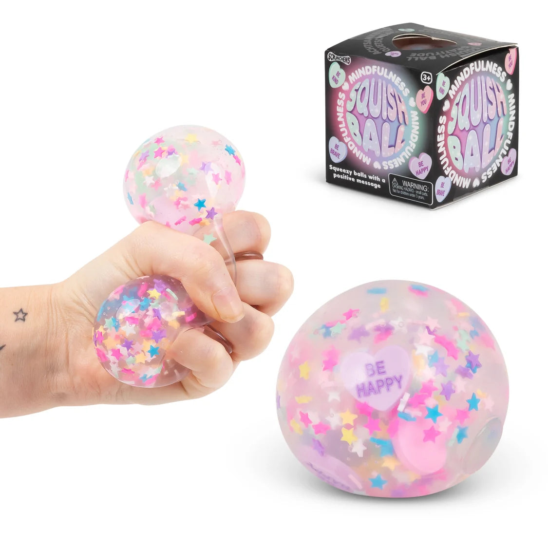 Pink squishy ball with confetti and 'Be Happy' text, held in a hand, next to its packaging.
