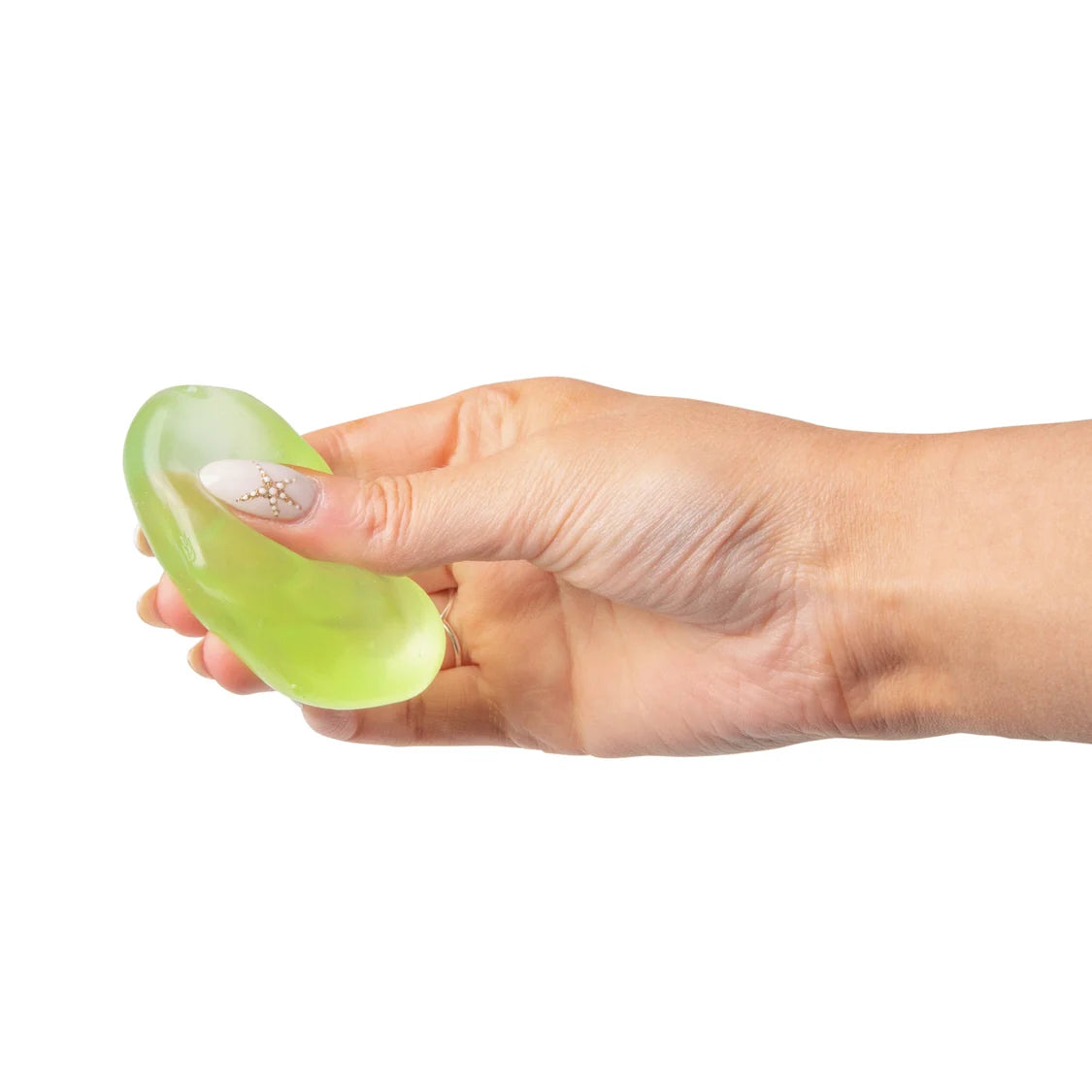 A hand holding a translucent light green sugar cube against a solid white background.