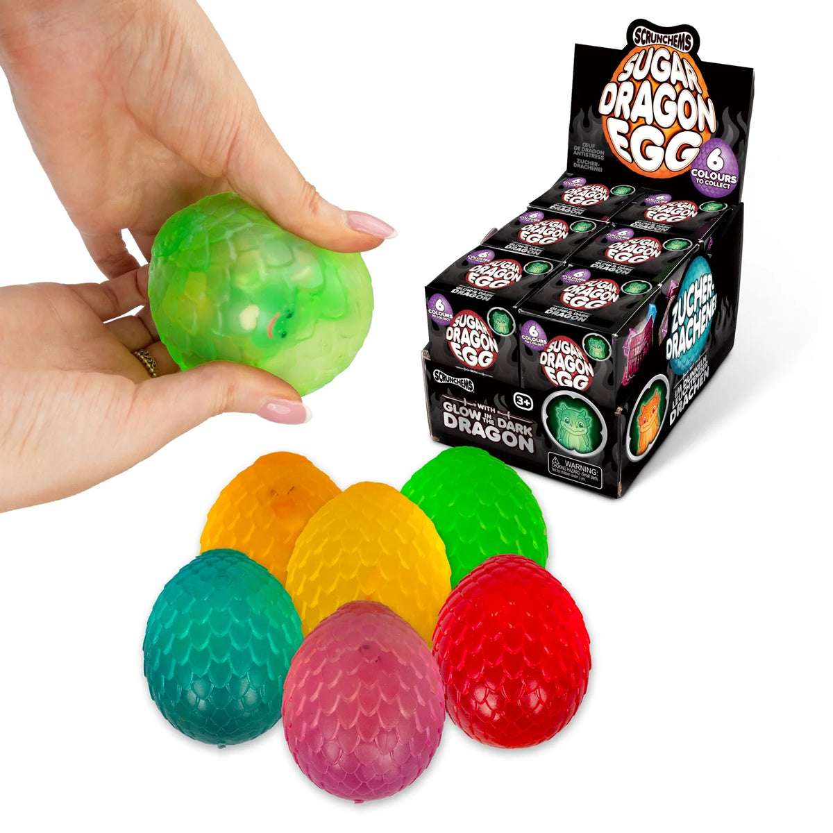 Colourful Scrunchems Sugar Dragon Eggs with a hand holding one, and a box of the product on a white background.