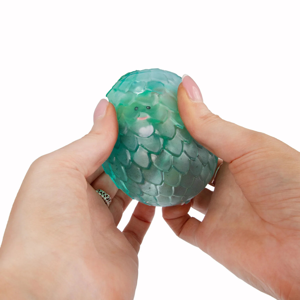 Hand holding a green Scrunchems Sugar Dragon Egg against a white background