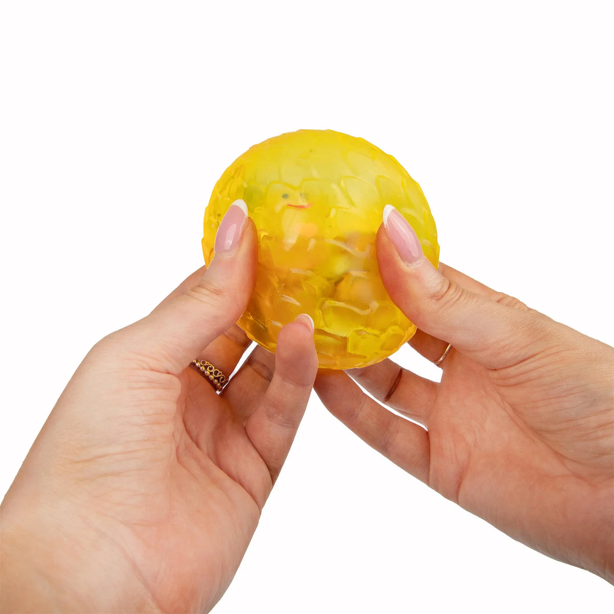 Yellow Scrunchems Sugar Dragon Egg held between two hands on a white background