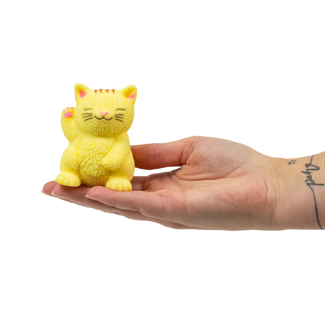 Yellow cat figurine held in a hand against a white background