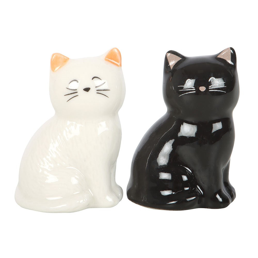 Two ceramic cat figurines, one white and one black, on a white background.
