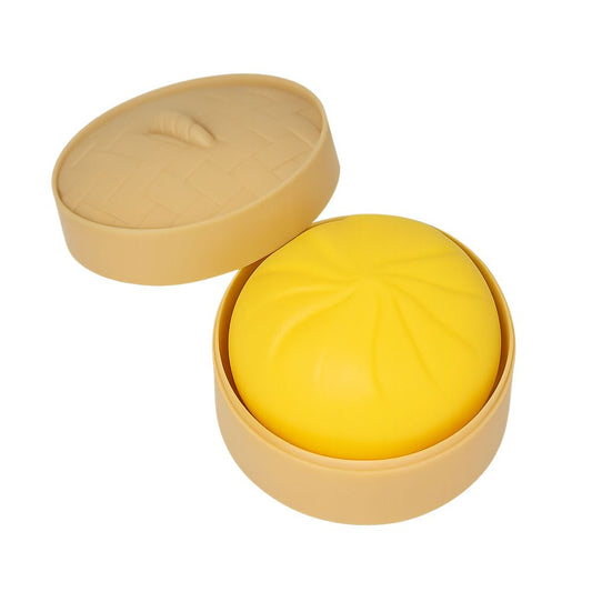 Yellow squishy dumpling in a beige container on a white background