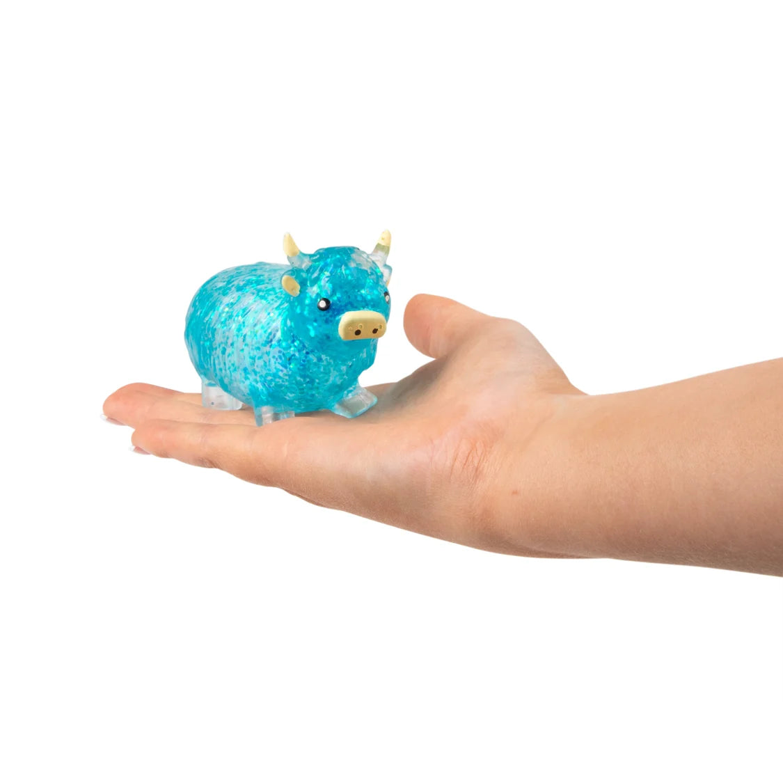 Small blue sugar highland cow toy held in a hand against a white background