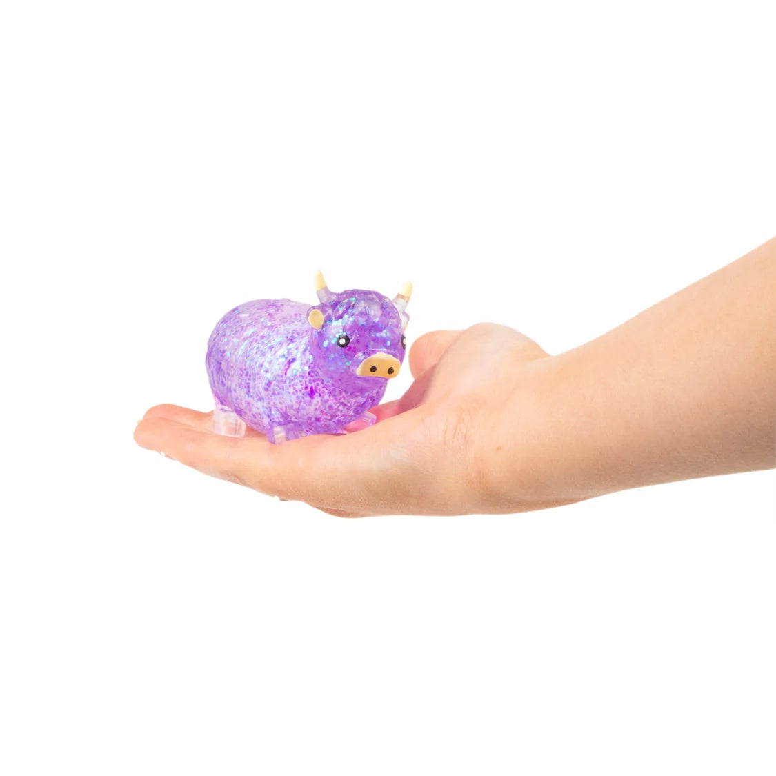 Hand holding a small purple sugar highland cow on a white background