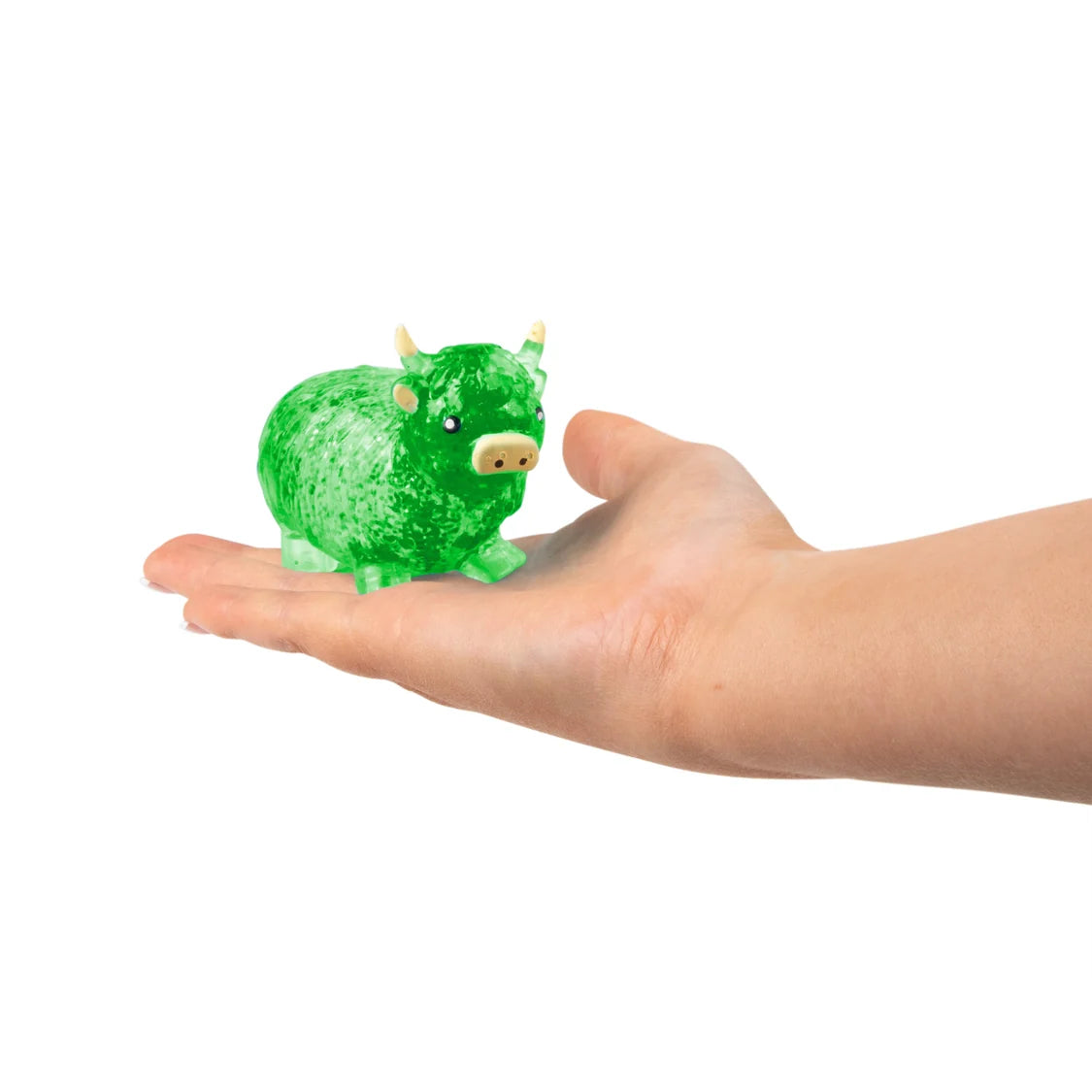 Small green sugar highland cow toy held in a hand against a white background